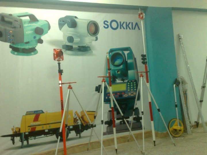 The Shahzad Brothers showroom in 2010, with a printed Sokkia banner behind survey tripods, prism poles and levelling staffs